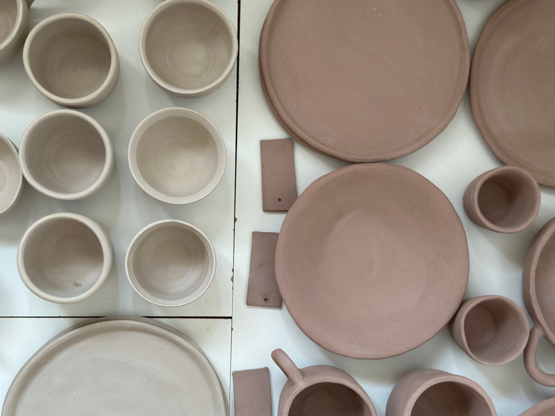 Platos, bols y tazas de cerámica sin esmaltar secándose en el taller